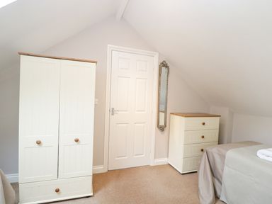 A bedroom with a wardrobe chest of drawers bed and mirror at The Brambles in Monmouth