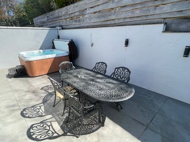 An outdoor patio with a hot tub and a metal table with six chairs at The Brambles in Monmouth