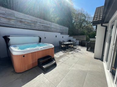 An outdoor terrace with a hot tub and a metal dining table with chairs at The Brambles in Monmouth