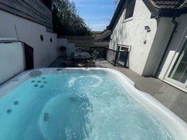 An outdoor patio with a hot tub table and chairs and a barbecue grill at The Brambles in Monmouth