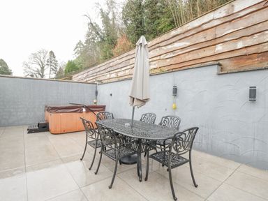 A patio with metal table and chairs an umbrella and a covered hot tub at The Brambles in Monmouth