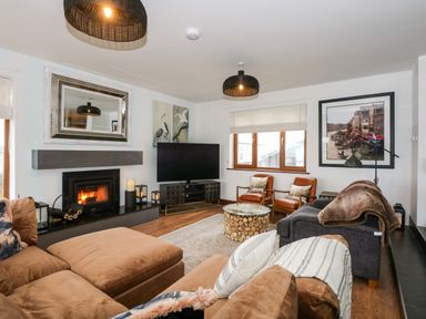 A living room with a fireplace television and seating at Swyn Llyr in Rhosneigr