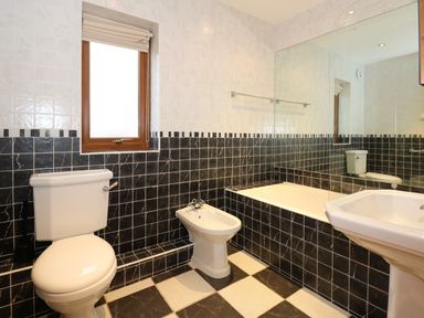 A bathroom with a toilet bidet bathtub sink and a window at Swyn Llyr in Rhosneigr