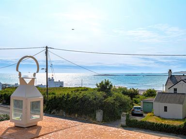 A coastal view with a white lantern on a balcony and houses near the sea at Swyn Llyr in Rhosneigr