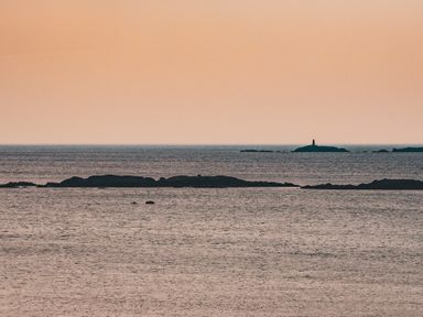 A sea view with several rocky islands and an orange sky at Swyn Llyr in Rhosneigr