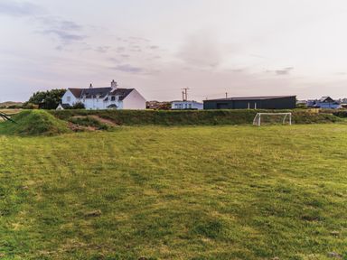 A field with a goal and nearby houses at Glanllyn Bach in Llanfaelog