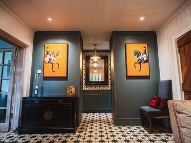 A hallway with paintings and a console table at Glanllyn Bach in Llanfaelog