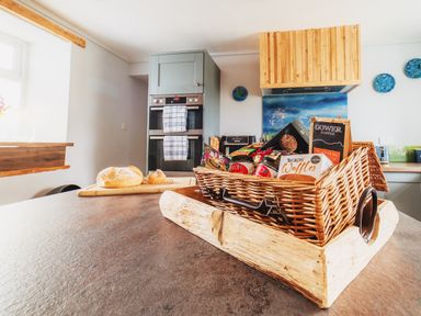 A kitchen with a basket of food and a loaf of bread at Glanllyn Bach in Llanfaelog