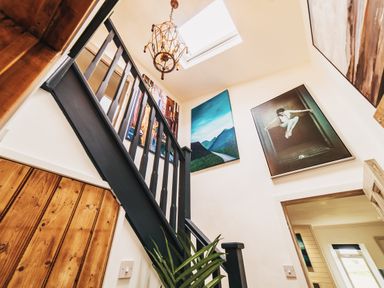 A staircase with a chandelier and artwork at Glanllyn Bach in Llanfaelog