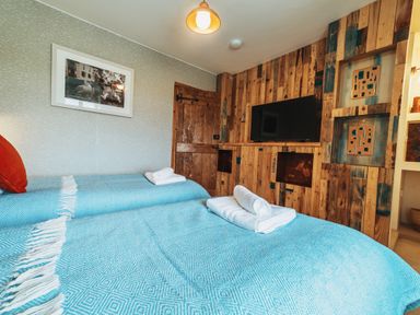 A bedroom with two beds and a television at Glanllyn Bach in Llanfaelog