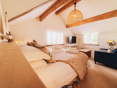 A bedroom with a bed, sofa and television at Glanllyn Bach in Llanfaelog