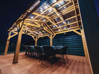 An outdoor dining area with a wooden pergola and chairs at Glanllyn Bach in Llanfaelog
