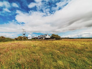 A house and power pole in a grass field at Glanllyn Bach in Llanfaelog