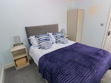A bedroom with a double bed blue patterned bedding two side tables with lamps and a closed wardrobe at Bluebell Cottage in St Brides-super-Ely near Cardiff