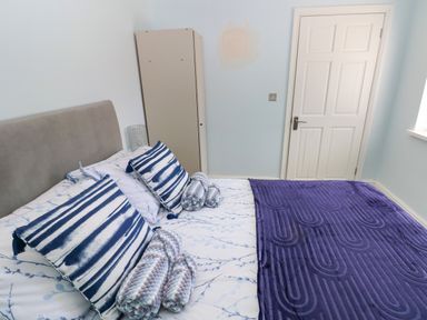 A bedroom with a bed with patterned pillows and blankets near a closed door at Bluebell Cottage in St Brides-super-Ely near Cardiff
