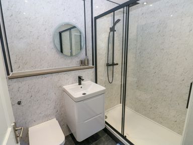 A bathroom with a shower enclosure a sink with faucets a mirror and a toilet at Bluebell Cottage in St Brides-super-Ely near Cardiff
