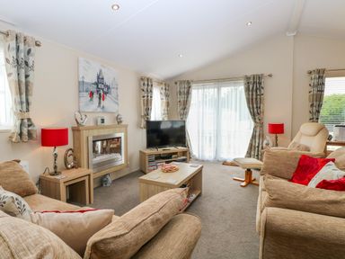 A living room with sofas a coffee table and a television at 21 Norman Drive Lodge in Burgh Castle