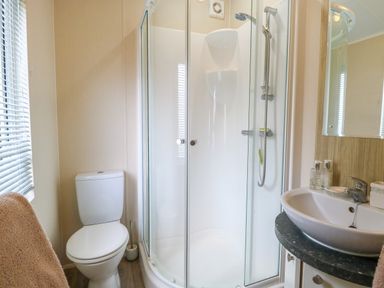 A bathroom with a toilet shower enclosure and sink at 21 Norman Drive Lodge in Burgh Castle