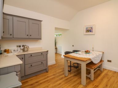 A kitchen with gray cabinets and a wooden dining table with chairs at The Farm Cottage in Athy County Kildare