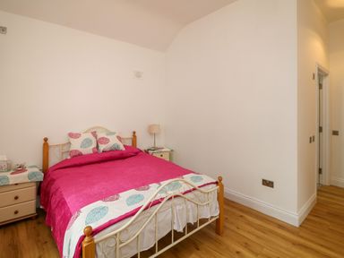 A bedroom with a double bed two bedside tables a lamp and wooden flooring at The Farm Cottage in Athy County Kildare