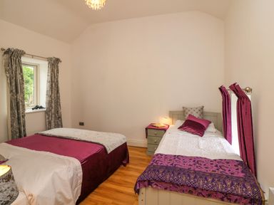 A bedroom with two beds a nightstand and curtains at The Farm Cottage in Athy County Kildare