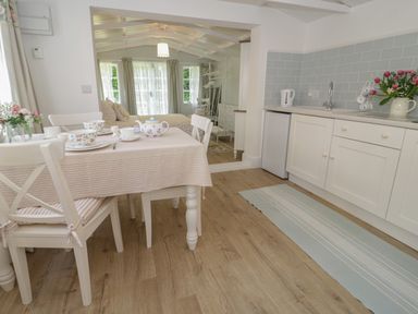 A kitchen and dining area with a table set for tea and a bed visible in the background at Ty Hafan in Mostyn