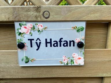 A wooden fence with a sign saying Ty Hafan decorated with pink roses at Ty Hafan in Mostyn