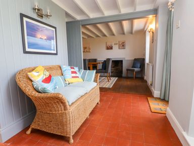 A sitting area with wicker sofa and dining room with chairs and table at Bryn Tirion in Morfa Nefyn