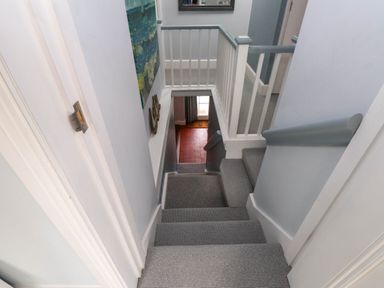 A staircase with grey carpet and white and grey painted railings and walls at Bryn Tirion Morfa Nefyn
