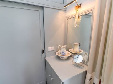 A corner with a cabinet topped with a pitcher and basin set and a small mirror next to a wall mirror at Bryn Tirion in Morfa Nefyn