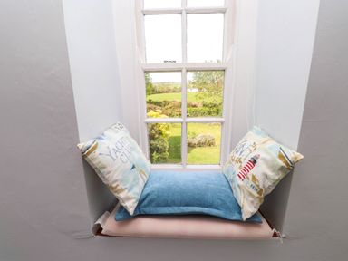 A window seat with three cushions overlooking a garden at Bryn Tirion in Morfa Nefyn