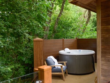 An outdoor deck with a hot tub and a chair with a white robe at 10 Stonerush Valley in Lanreath near Looe