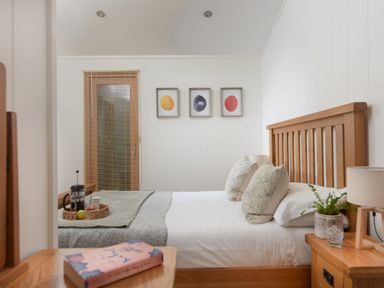 A bedroom with a wooden bed frame a gray blanket and three framed pictures on the wall at 10 Stonerush Valley Lanreath near Looe
