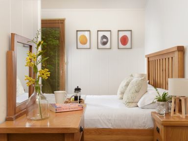 A bedroom with a wooden bed and side tables with lamps and a mirror on a dresser at 10 Stonerush Valley Lanreath near Looe