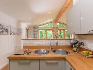 A kitchen countertop with two sinks a cutting board with bread a knife a pitcher of water with lemon and fruit at 10 Stonerush Valley Lanreath near Looe