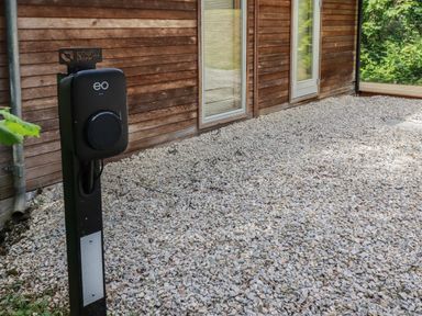 An outdoor area with a wooden wall and electric vehicle charging station on gravel at 10 Stonerush Valley Lanreath near Looe