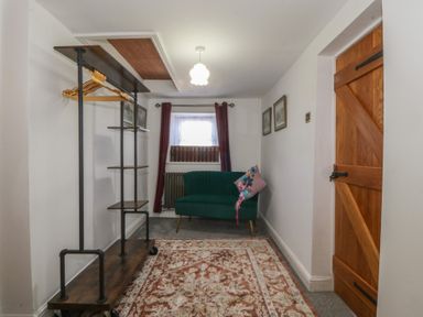 An entryway with a sofa and coat rack at Tan Y Merddyn in Ceunant near Llanrug