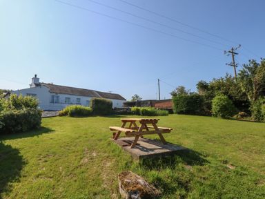 A garden with a picnic table and a house in the background at Tan Y Merddyn Ceunant near Llanrug