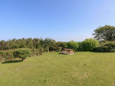 A garden with a picnic table and shrubs at Tan Y Merddyn Ceunant near Llanrug