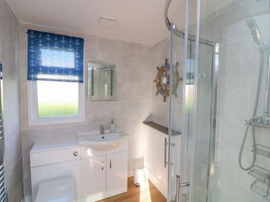 A bathroom with a sink vanity toilet shower and a nautical themed window blind at The Sail Loft in Norton Park near Dartmouth