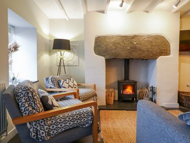 A sitting room with armchairs a stove fireplace and a floor lamp at Ty Dyffryn in Llan Ffestiniog