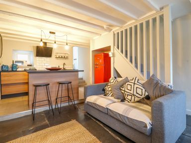 A kitchen and living area with a grey sofa and a red refrigerator at Ty Dyffryn in Llan Ffestiniog