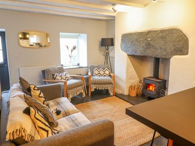 A living room with sofa chairs a rug and a wood burning stove at Ty Dyffryn in Llan Ffestiniog