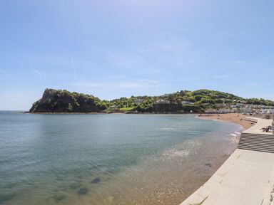 A beach with a curved concrete promenade and steps leading to the water at Beach Hut 5 in Shaldon