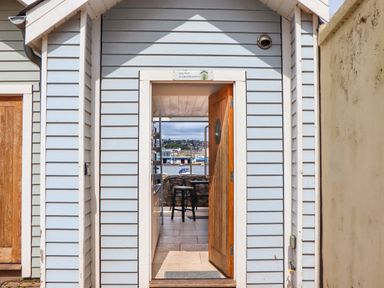 An open wooden door on a light blue beach hut showing a view of a chair and water beyond at Beach Hut 5 in Shaldon