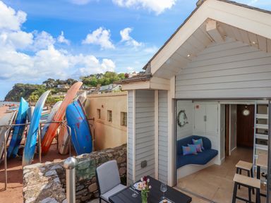 A beach hut patio with table and chairs next to kayaks on the beach at Beach Hut 5 in Shaldon