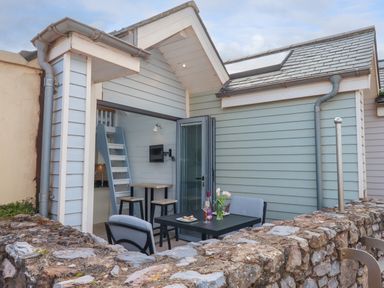 A small outdoor patio with a table and chairs outside a light blue wooden cottage at Beach Hut 5 in Shaldon