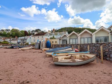 Boats resting on a sandy beach in front of houses and beach huts at Beach Hut 5 in Shaldon