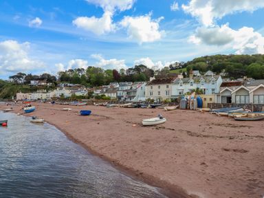 A beach with small boats on the sand and a row of houses along the shore at Beach Hut 5 in Shaldon