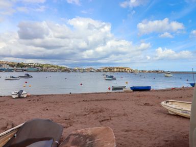 A sandy beach with small boats and a view of a waterfront town across the water at Beach Hut 5 in Shaldon
